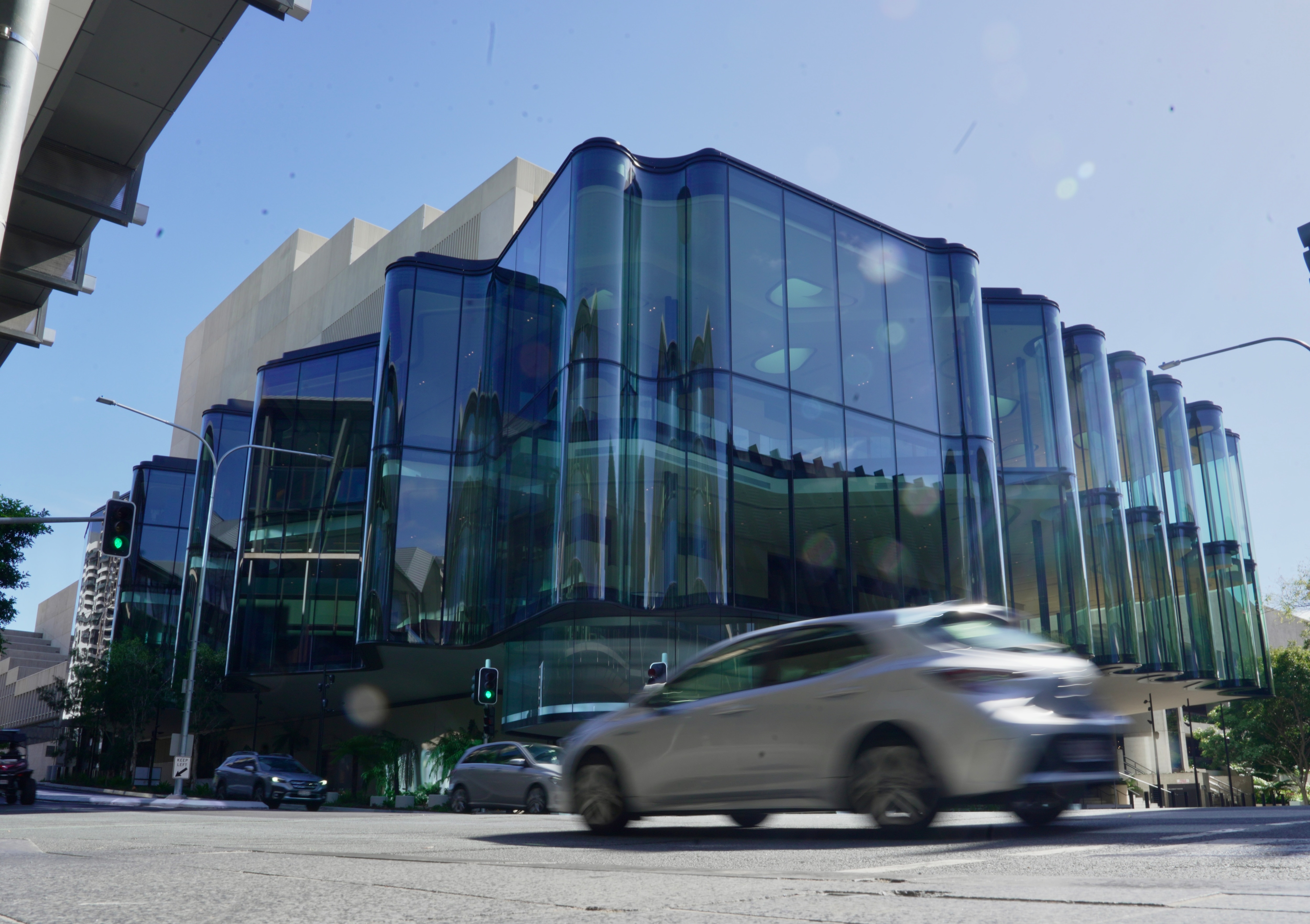 A car is out of focus as it drives past the large Glasshouse Theatre in Brisbane.