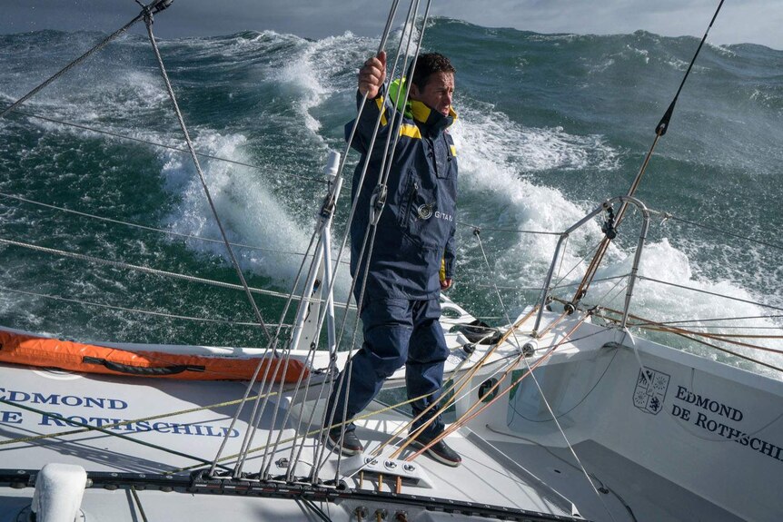 Yachtsman Sebastien Josse standing on his boat amid high seas