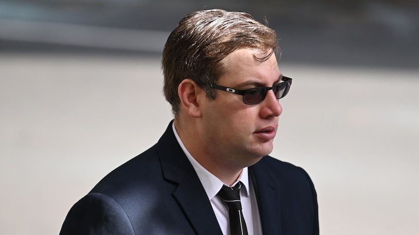 Dominic Gaynor arrives at court wearing a suit and sunglasses