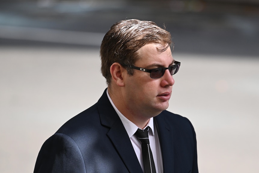 Dominic Gaynor arrives at court wearing a suit and sunglasses