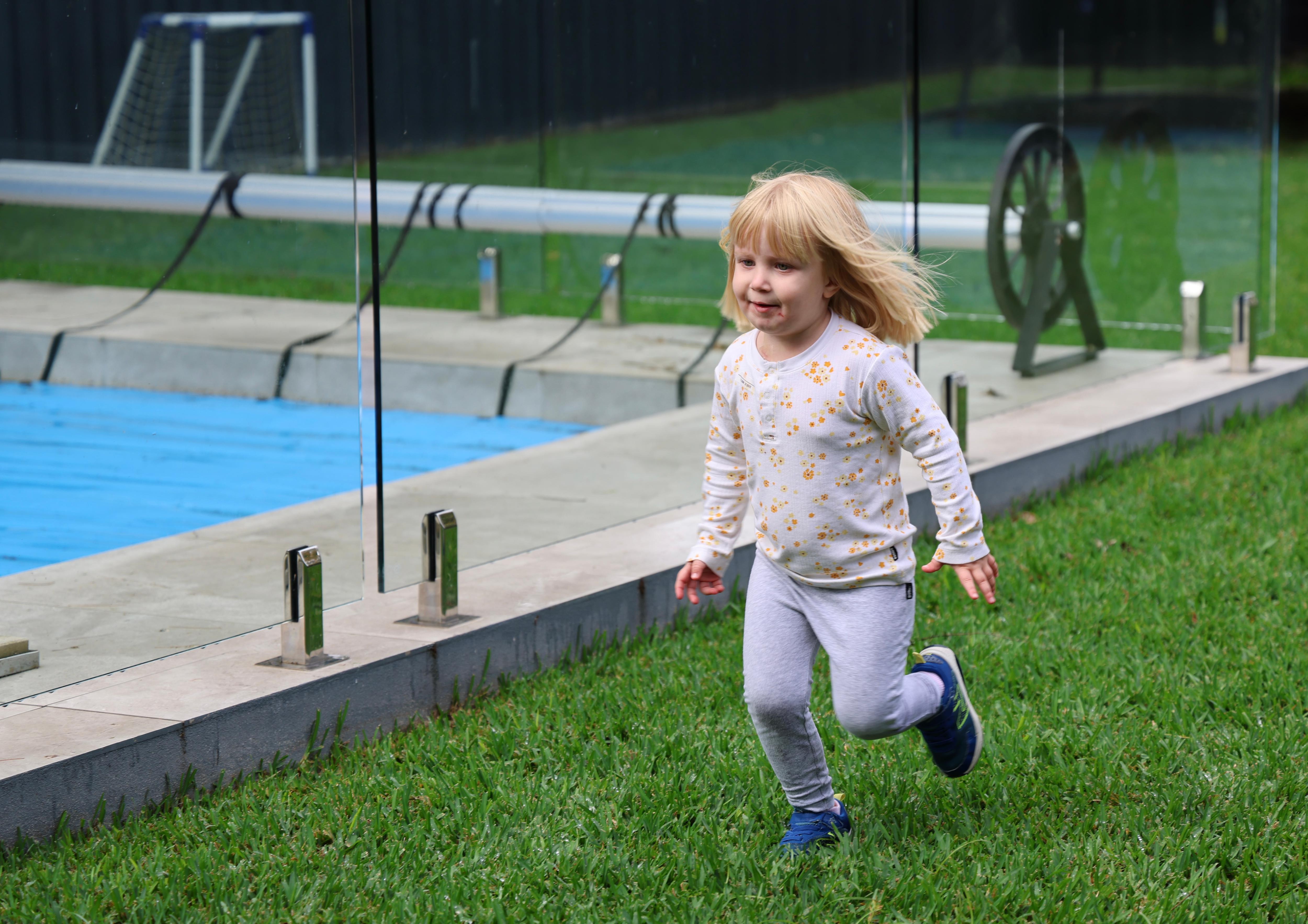 little girl runs by a pool