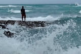Man stands on rocks as rough surf brews in Hawaii as Hurricane Lane nears