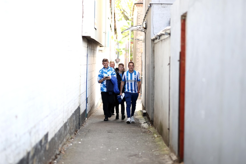Fans walk down a white-washed alley