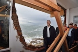 Bill shorten standing next to a hole in the wall made by damaging waves.