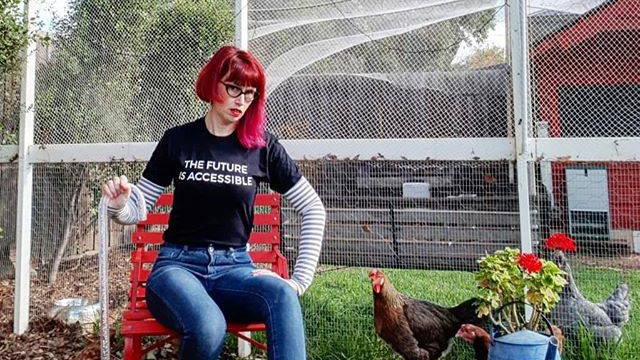 Michelle Roger with her chooks, reading a tshirt that says 'the future is accesible'.