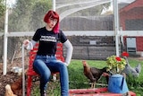 Michelle Roger with her chooks, reading a tshirt that says 'the future is accesible'.