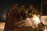 Israeli soldiers ride on their armoured personnel carrier
