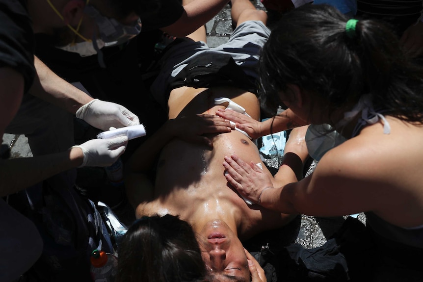 People come to the aid of an anti-government protester wounded during clashes with police.