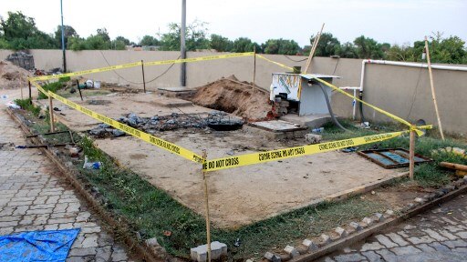 The outside of an underground septic tank is surrounded by tape marked with 'crime scene do not cross'