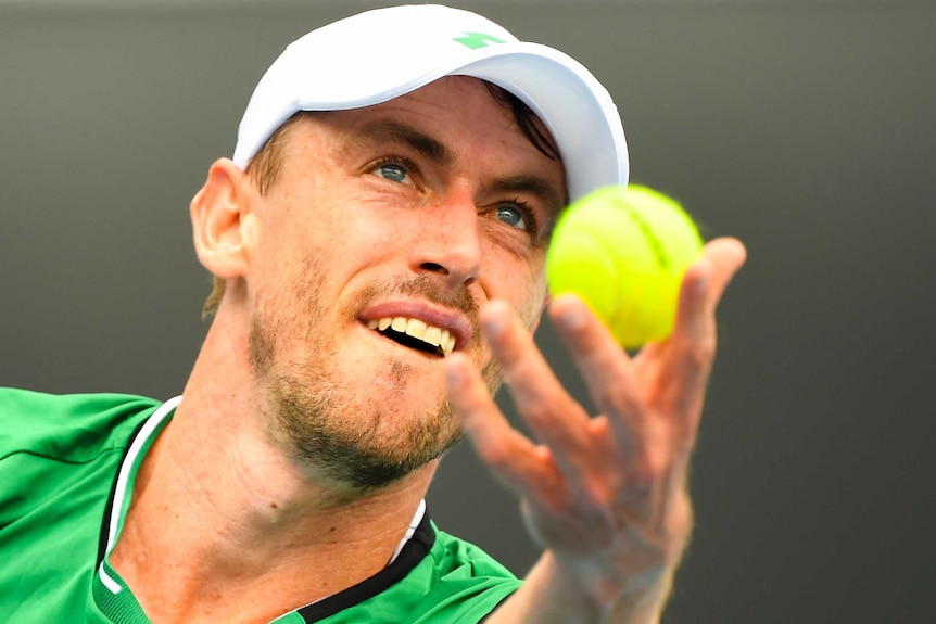 John Millman looks intently as he tosses the ball up to serve