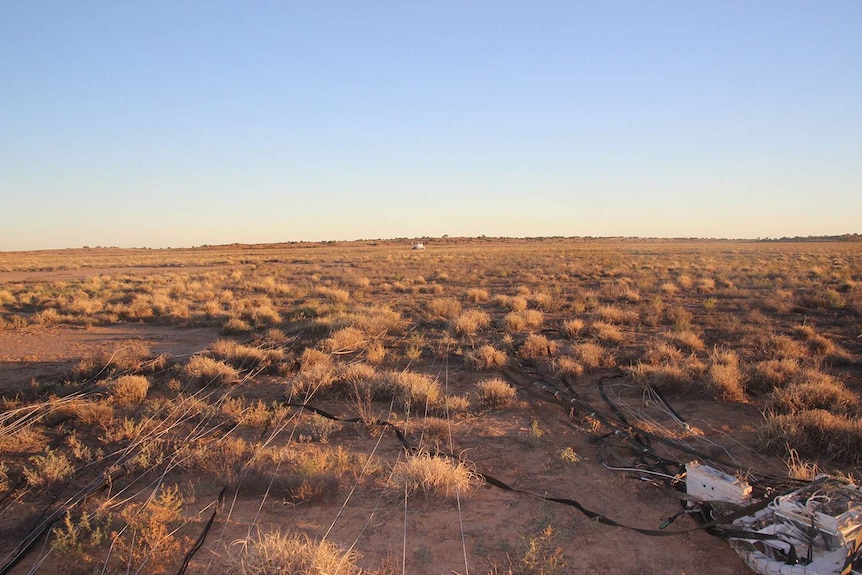 Strings of NASA scientific balloon in the foreground stretching back to its white payload bucket, seen on the horizon.