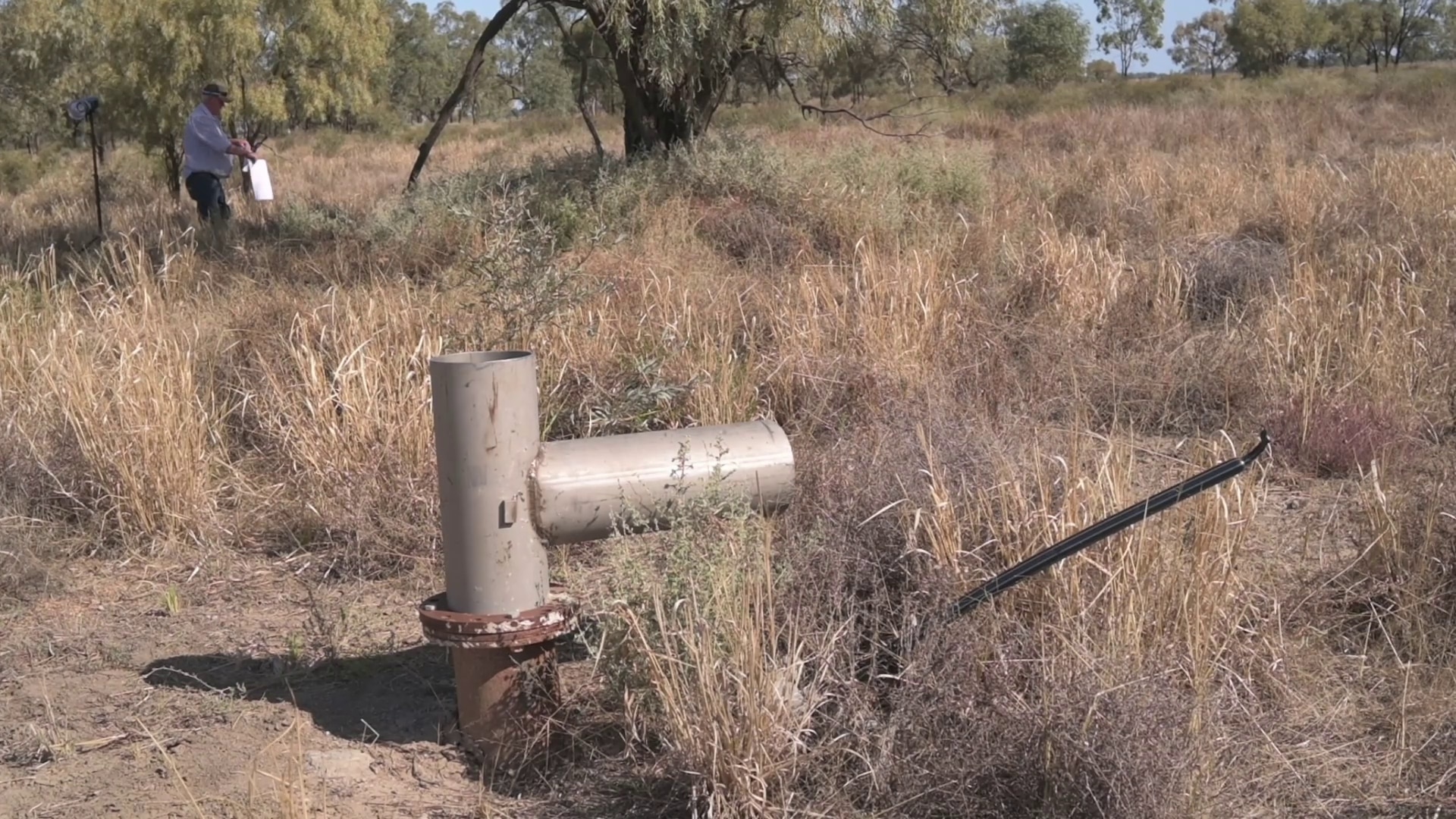A pipe in the ground with a man in the distance