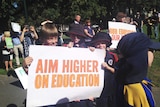 School children hold a sign at a rally in Hobart over cuts to the education budget.