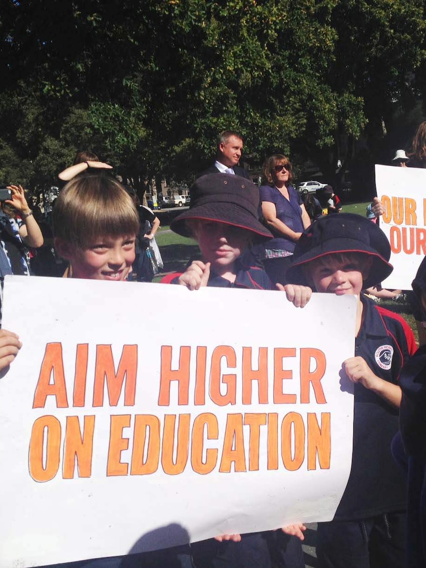 School children hold a sign at a rally in Hobart over cuts to the education budget.