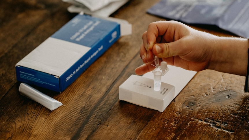 A hand squeezes a dropper above a test tube sitting