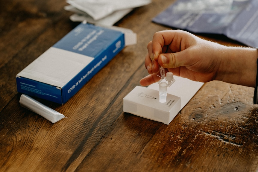 A hand squeezes a dropper above a test tube sitting