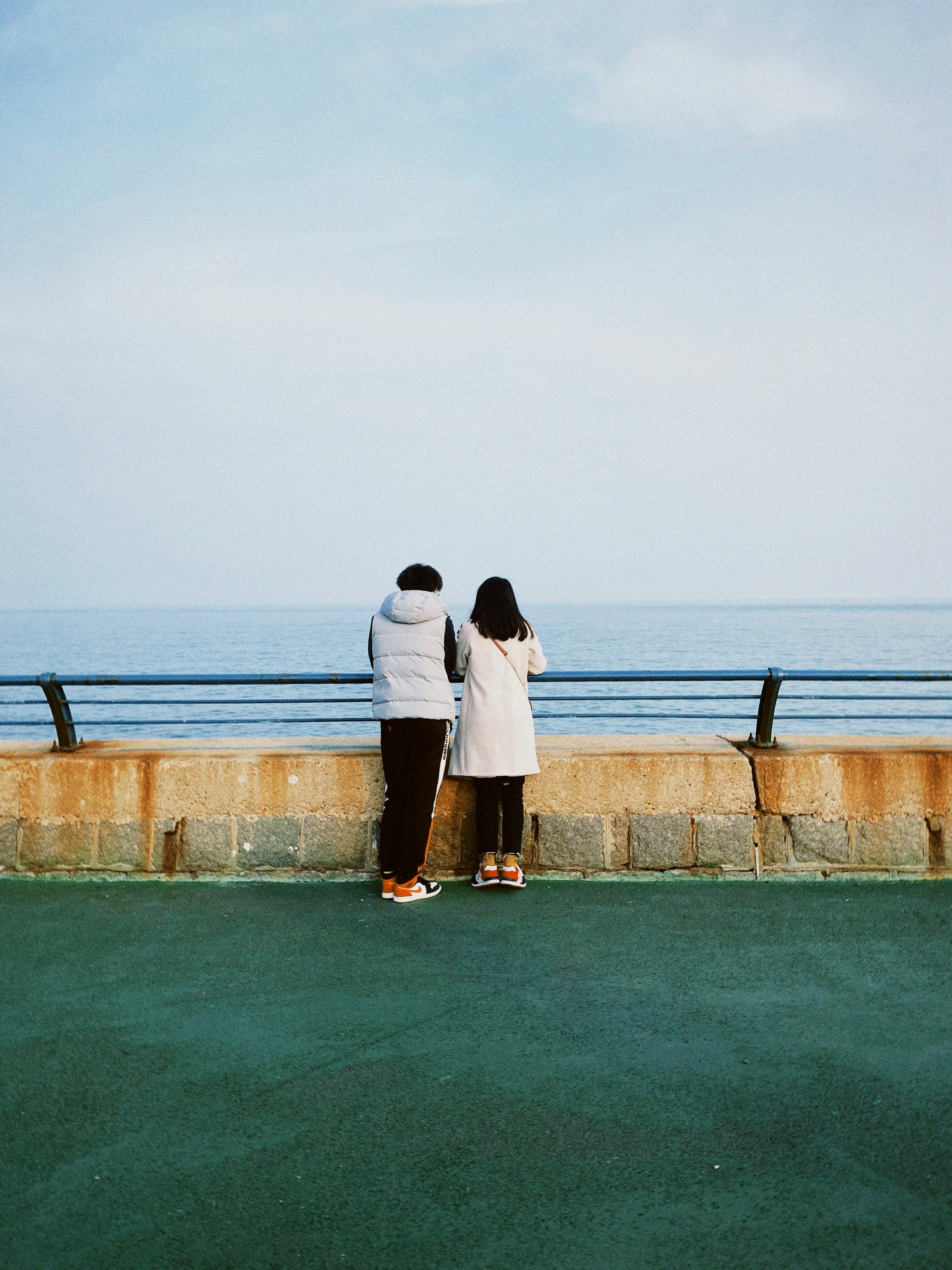 couple wearing warm clothes stand together looking out at the water