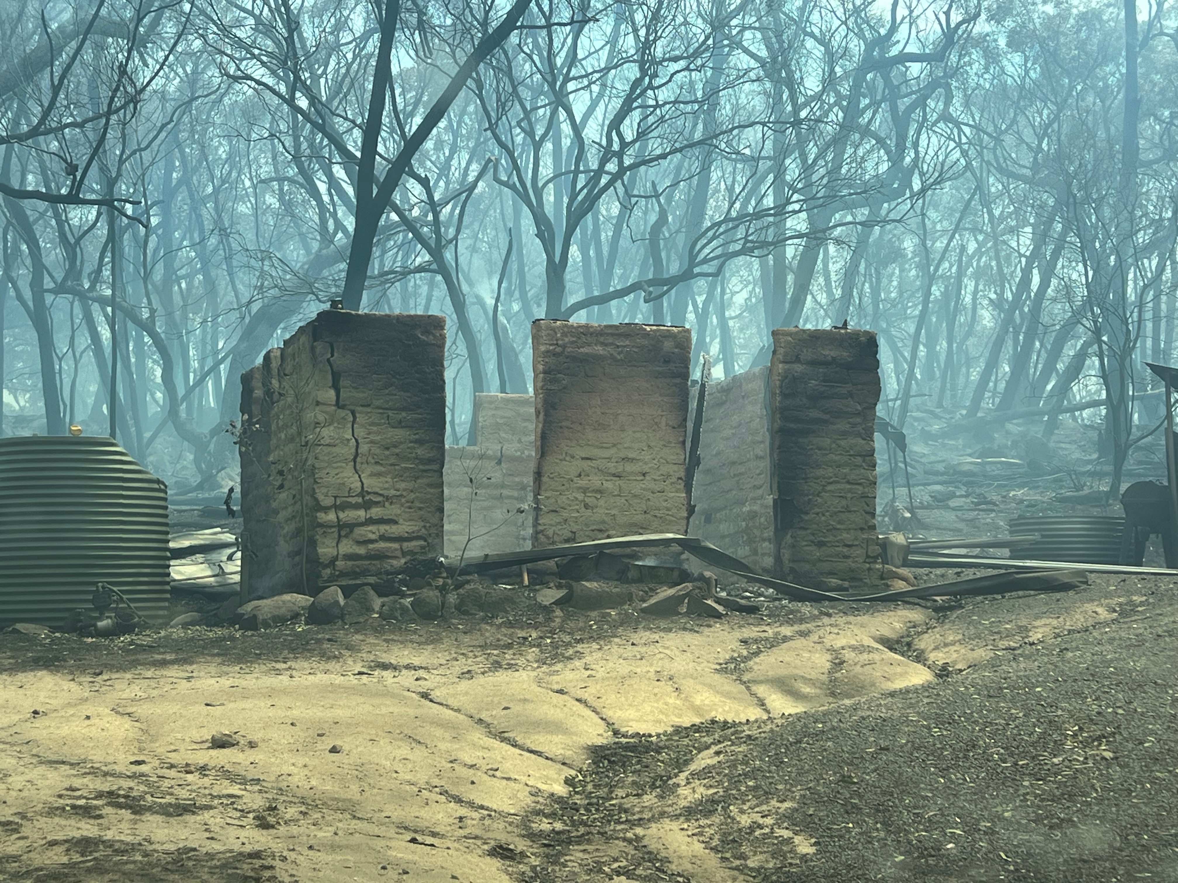 Os restos de um edifício após um incêndio que atingiu uma propriedade perto de Longwood.