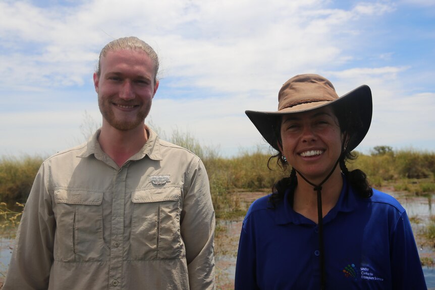 Man and woman smiling at camera with wetlands behind them 