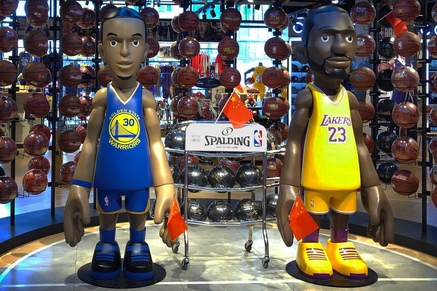 Statues of Steph Curry and LeBron James hold Chinese flags at an NBA merchandise store in Beijing.
