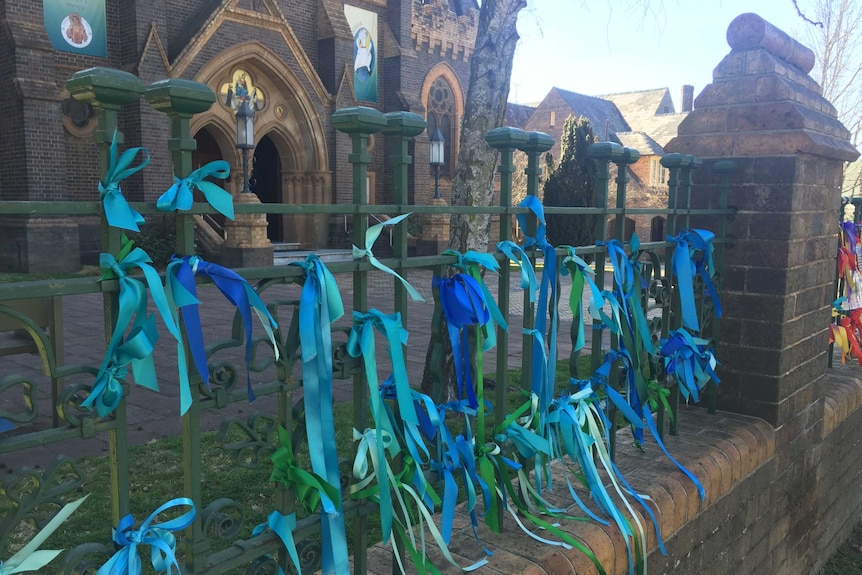 Blue ribbons tied to the fence of the Armidale Catholic Cathedral.