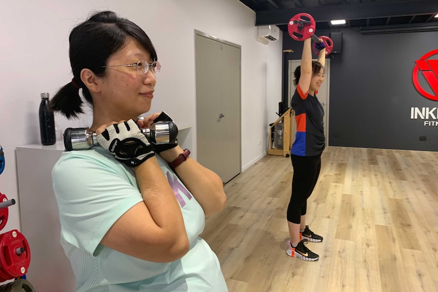 A woman lifting a dumbbell in a gym