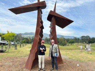 Photo of two men posing under a big statue