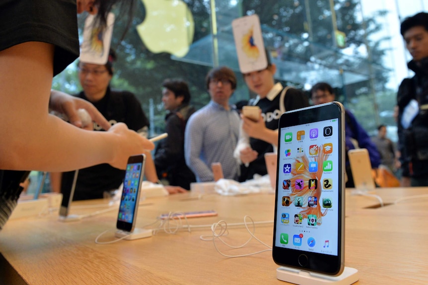 The iPhone 6s Plus on a display table at a Tokyo Apples store as customers look on.