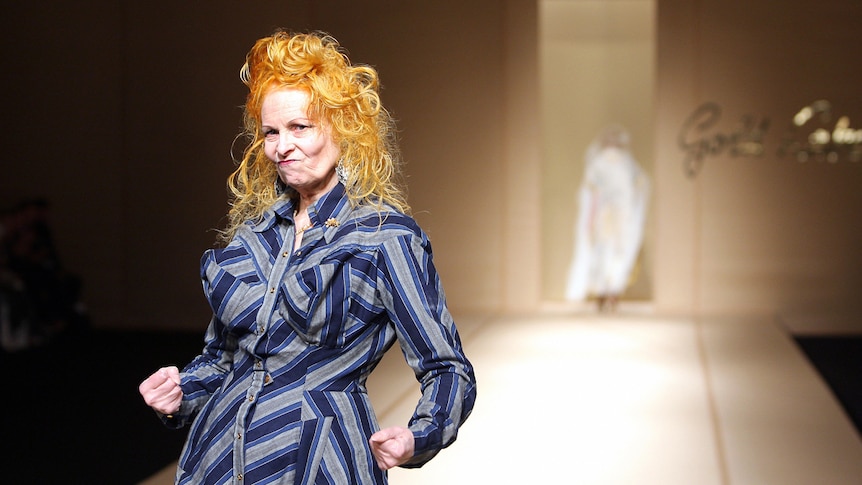 Vivenne Westwood with orange curly hair, wearing her own blue and grey striped dress, at end of runway, 2007 Paris Fashion Week
