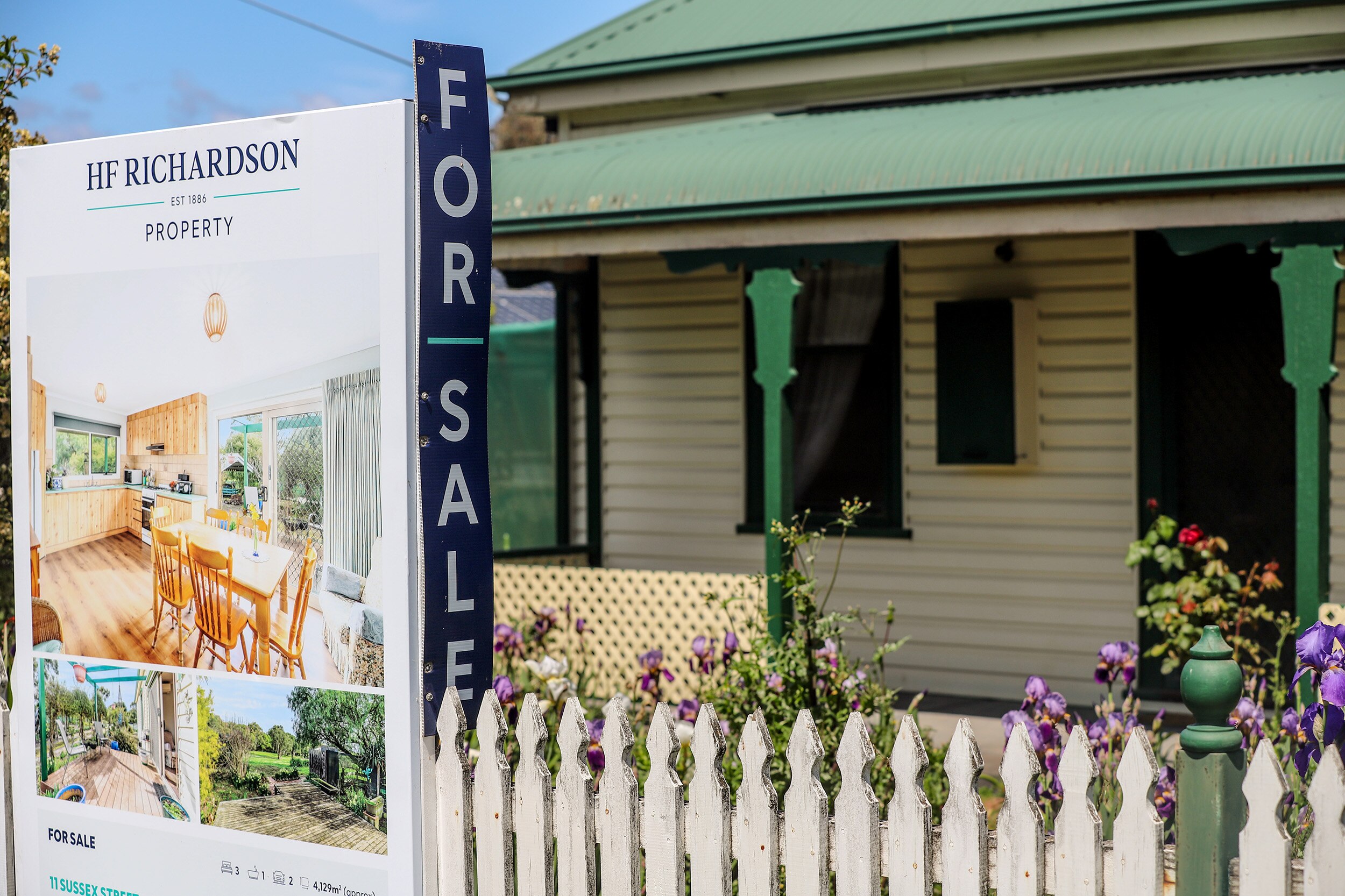 A For Sale sign sits outside an older regional detached home