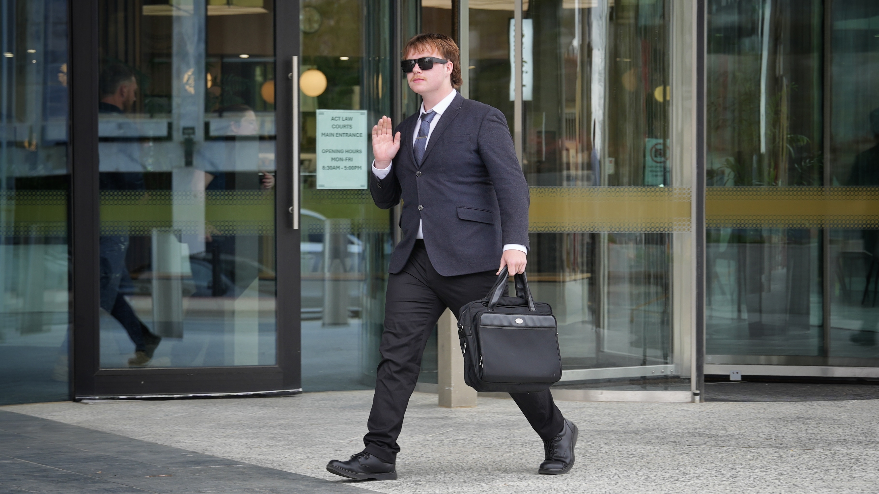 A man in suit and tie walks along carrying a briefcase.