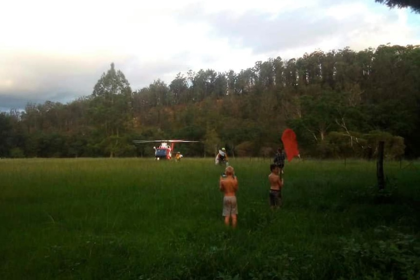 A helicopter in a field with people waiting for supplies.