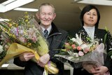 Charles Jenkins and his wife Hitomi Soga hold flowers and smile after arriving on home soil