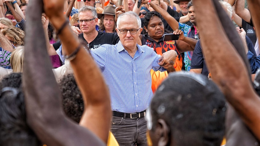 Malcolm Turnbull holds the hands of people in a dancing circle at Garma Festival.