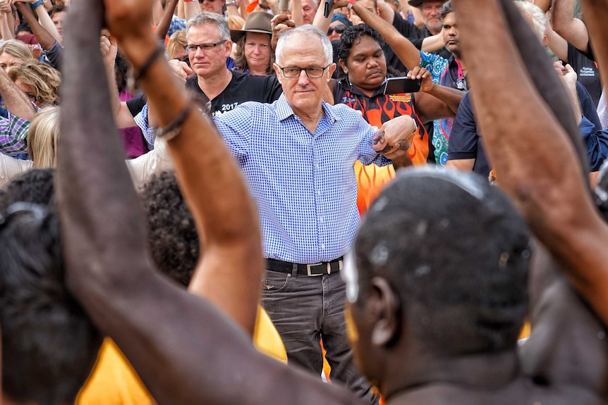 Malcolm Turnbull holds the hands of people in a dancing circle at Garma Festival.