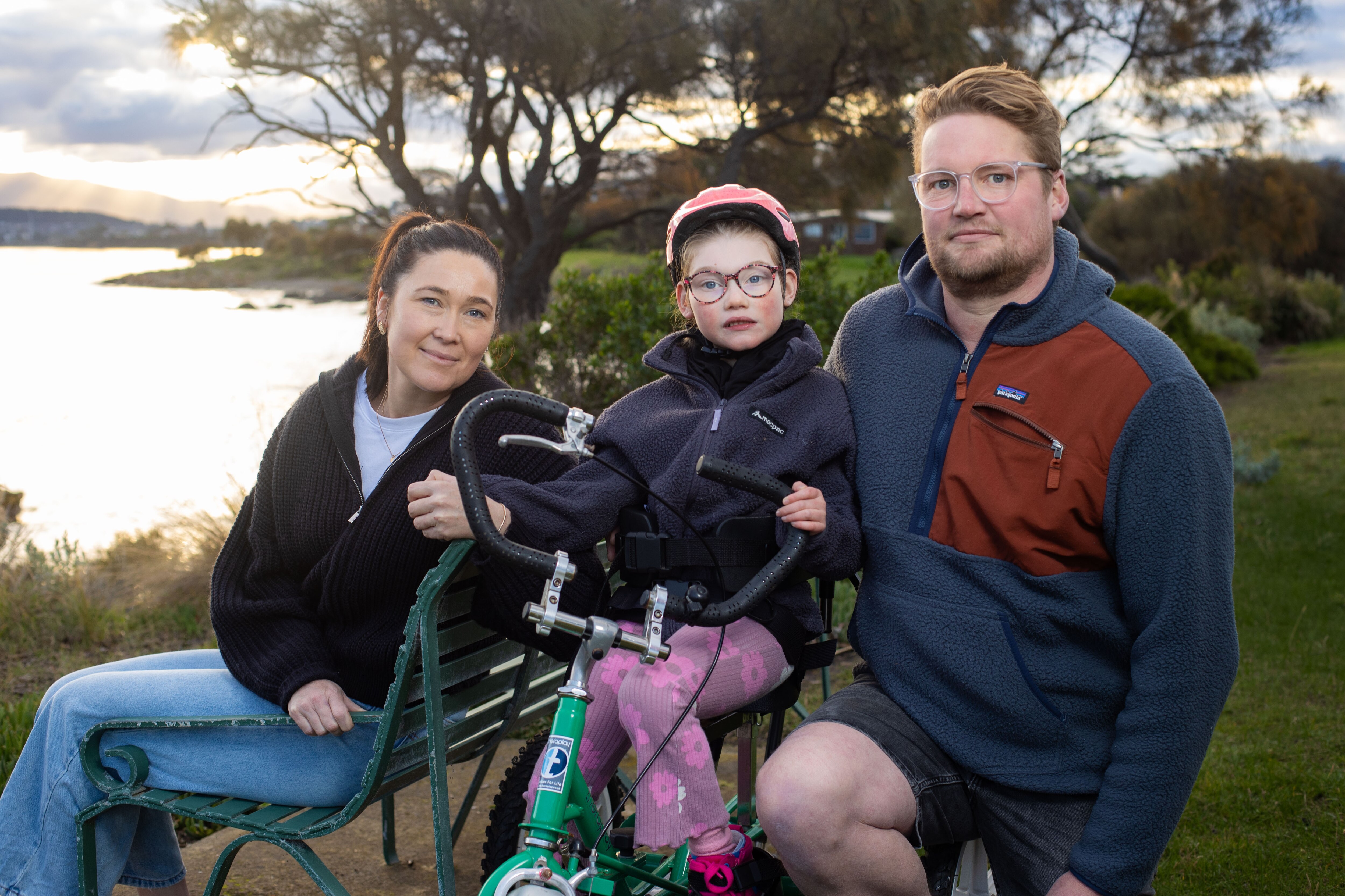 three children ride bikes down a path