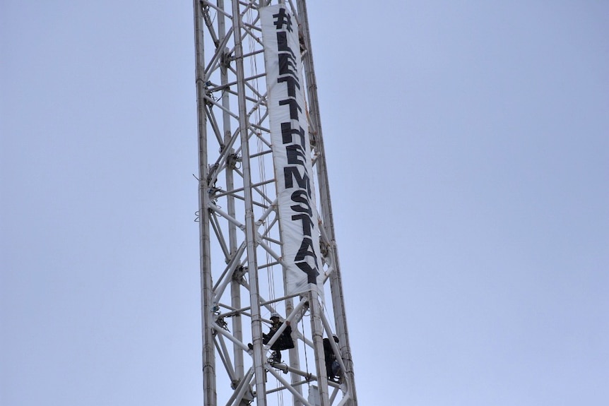 Activists hang a banner in support of asylum seekers on Melbourne's 162-metre tall Arts Centre spire.