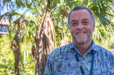 A man smiles while standing outside at Charles Darwin University.