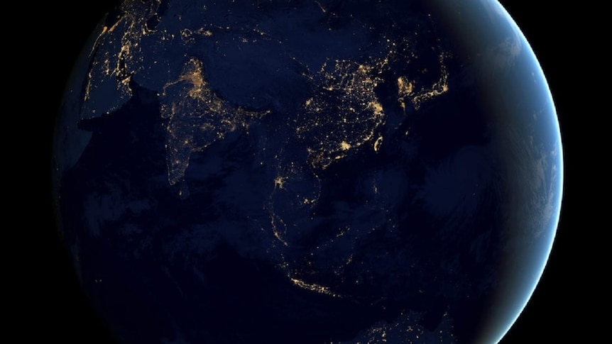 View of the Earth from space in darkness, with light visible in cities on different continents.