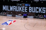 An empty NBA court, with screens that read 'MILWAUKEE BUCKS', 'NBA PLAYOFFS'. 'BLACK LIVES MATTER' is printed on the court