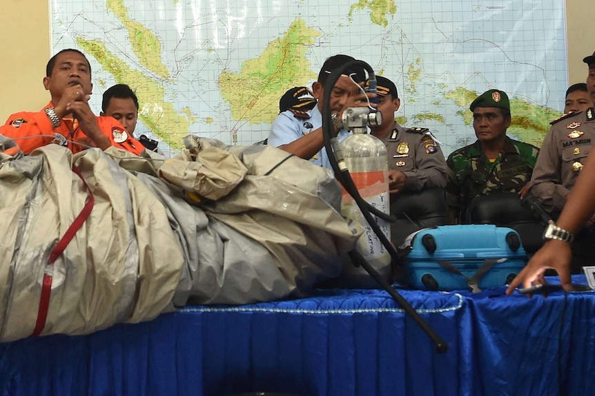 Members of the Indonesian air force show items retrieved from the Java sea during search and rescue operations for the missing AirAsia flight QZ8501