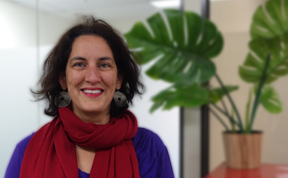 A woman looks at the camera smiling.