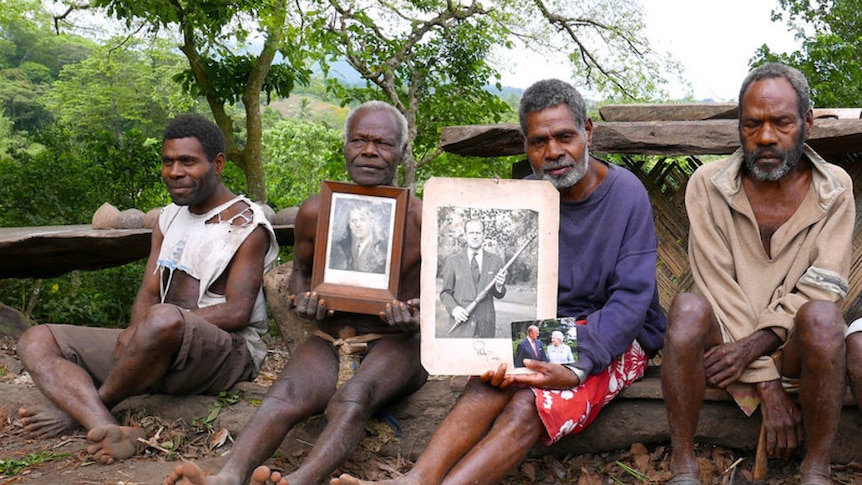 Four Tanna men sit holding photographs of Prince Philip
