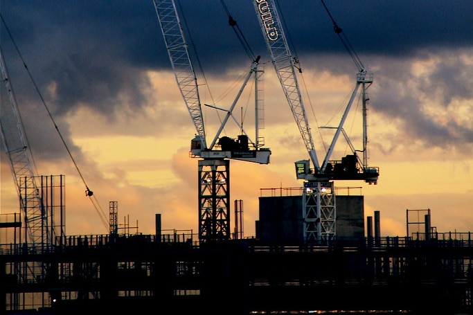 Construction cranes over high-rise buildings in Melbourne at sunset