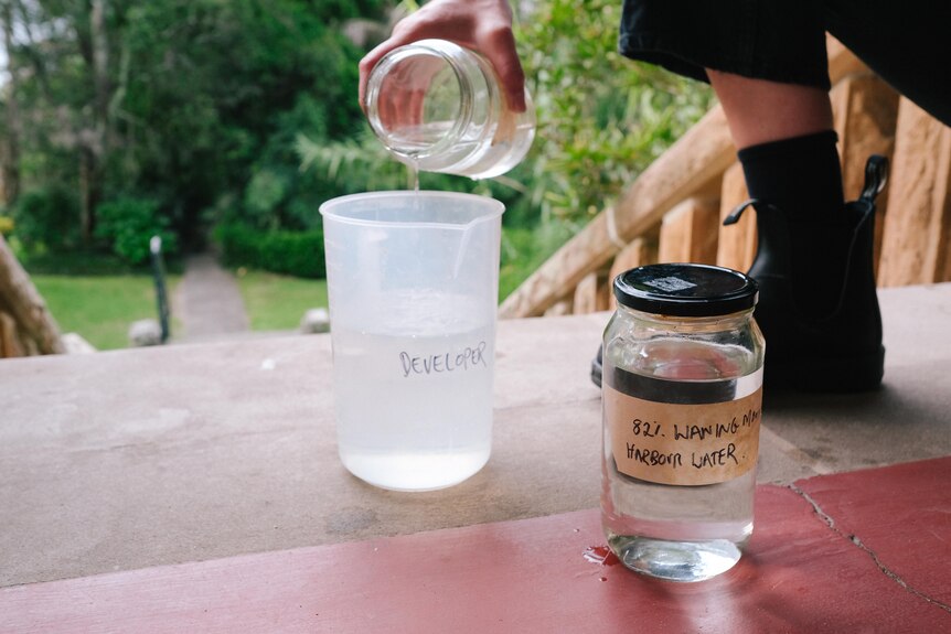 Sammy Hawker pouring harbour water from a jar into a plastic just labelled 'developer' .