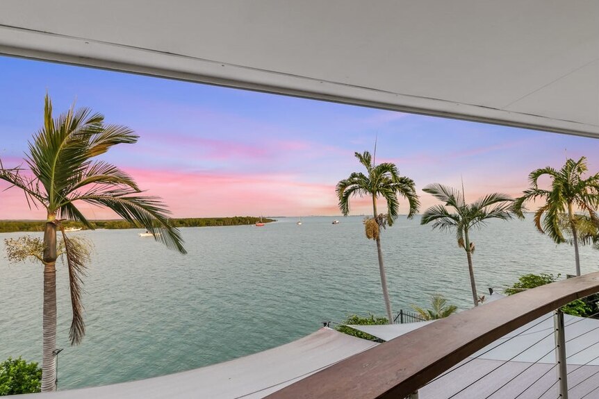 A spectacular sunrise or sunset over the water, viewed from a verandah.