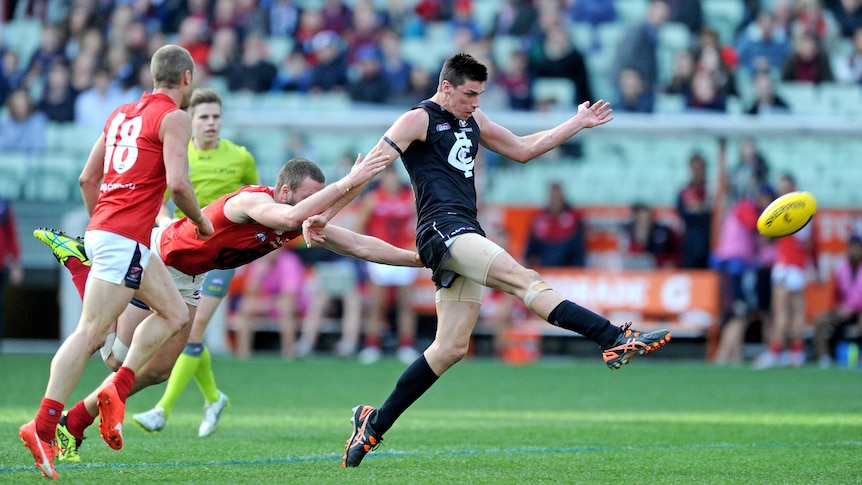 Matthew Kreuzer of the Blues beats a tackle by Max Gawn of the Demons and kicks a goal