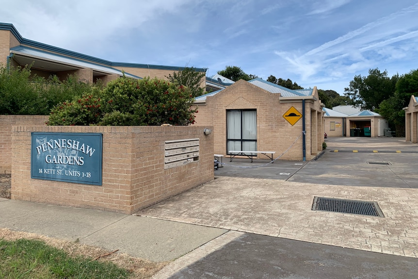 The outside of a housing complex, with a sign saying Penneshaw Gardens.