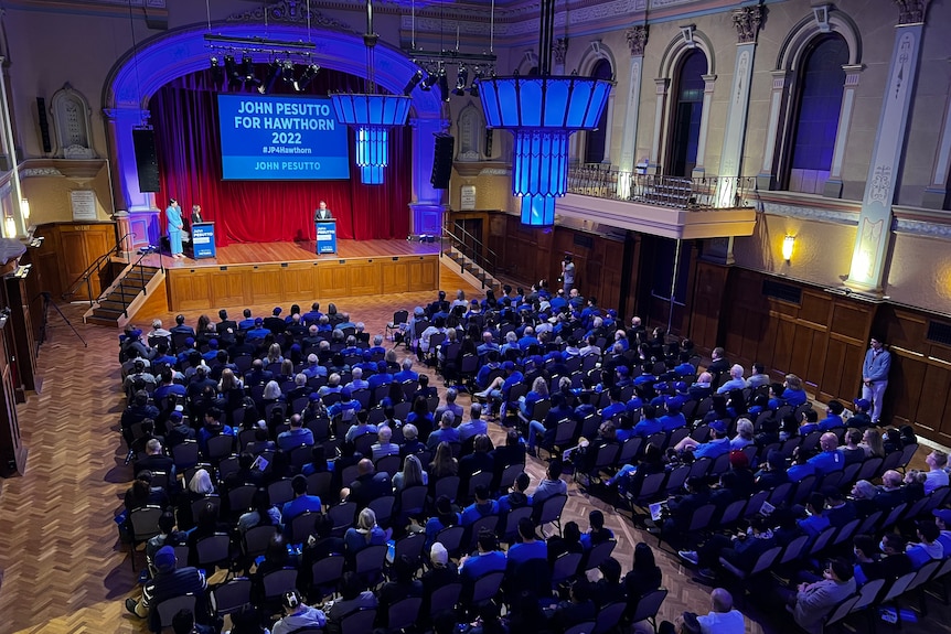 A large hall filled with people sitting in rows.