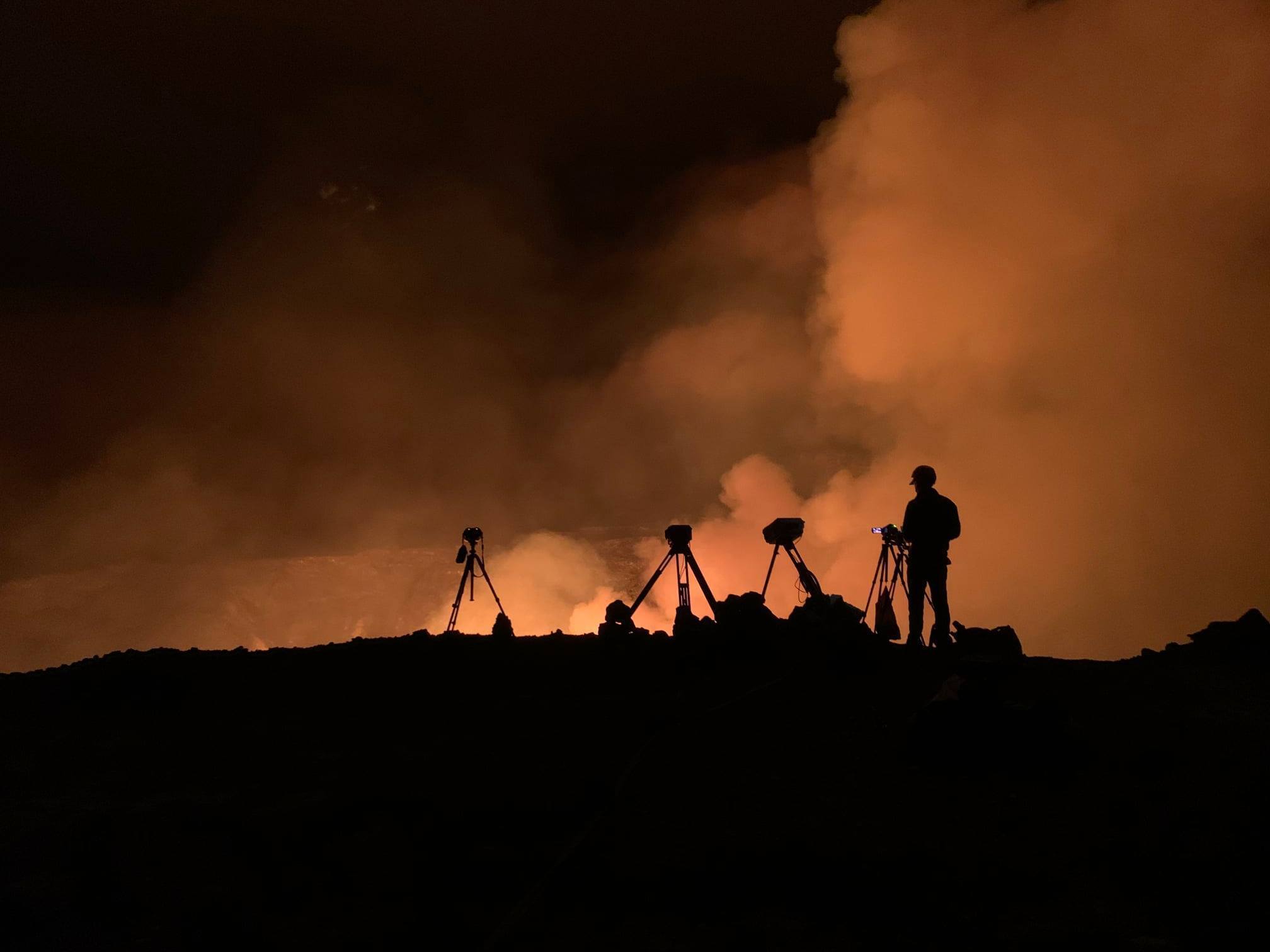 people stand near a volcano eruption
